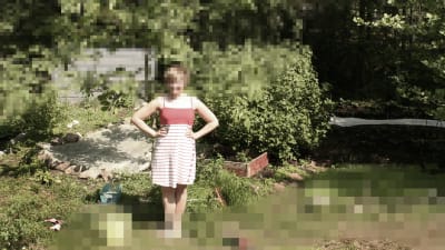 En kvinna står i en trädgård, bilden är delvis pixelerad och otydlig.