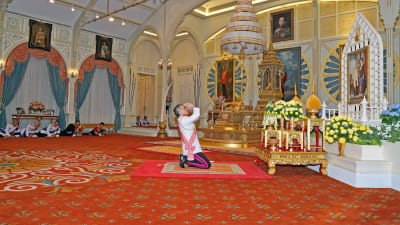Thailands nye kung Vajiralongkorn knäböjer inför ett porträtt av sin far, kung Bhumibol