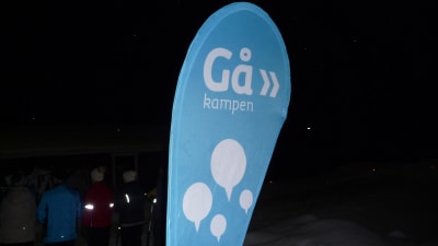 turkosfärgad gåkampen-skylt som finns ute i samband med en gåfest.