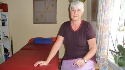 Agneta Westerlund vid sin privata mottagning. Sitter bredvid ett massagebord.