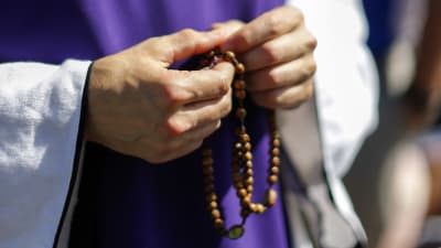 Händer som håller i ett katolskt radband
