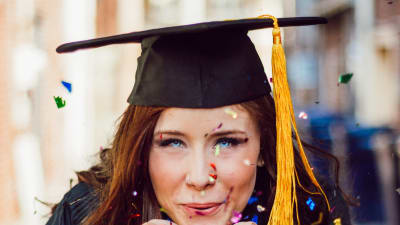 en ung tjej med amerikansk examensmössa blåser glitter omkring sig