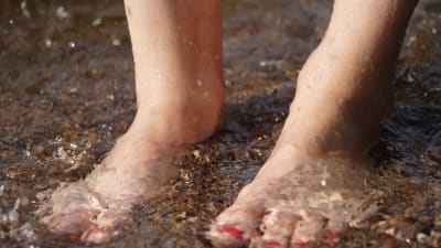 Fötter med lackade naglar i vatten