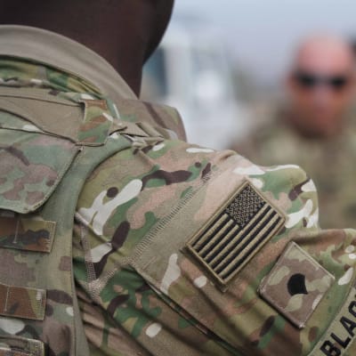 En amerikansk soldat syns på bilden. Bilden är en närbild så bara soldatens axem pch sidan av huvudet syns.
