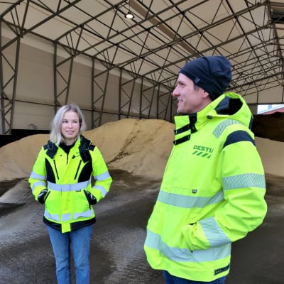 En kvinna och en man i arbetskläder står och diskuterar. 