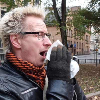 Närbild på Jonas Francks ansikte när han nyser och för en vit näsduk mot ansiktet.