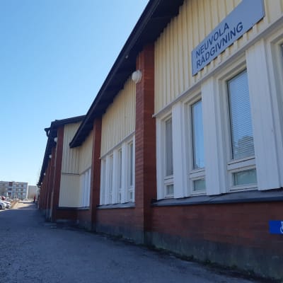 Ett gulmålat större hus, ett affärscenter i Sjundeå. På vägen en skylt som berättar att kommunen har sin rådgivning där.