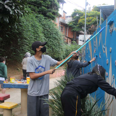 Nuoret maalaavat siniselle pohjalle seinään Puutarha-nimistä teosta Brasilian Sao Paolossa.