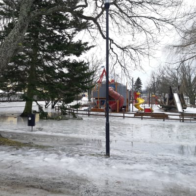 En lekpark för barn på vintern då marken är täckt av is och vatten.