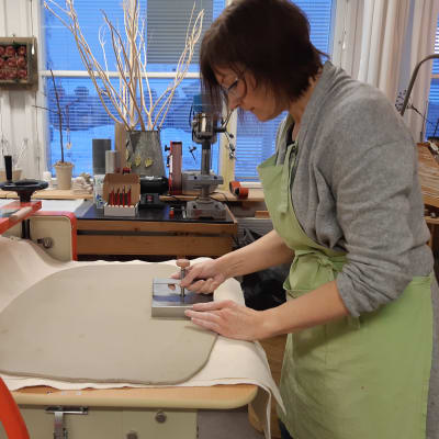 Catharina Borg-Wilén tar ut kakel ur leran med hjälp av en kakelform.
