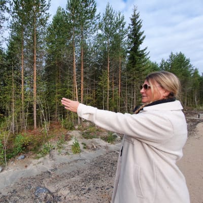 Pirjo Siermala osoittaa metsää Korvenkylässä ja näyttää aluetta, johon tulee rakentumaan muutaman vuoden sisällä omakotitaloja.