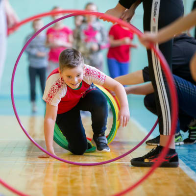 En pojke tar sig igenom en hinderbana av hula hula-ringar på en skolgymnastiklektion.