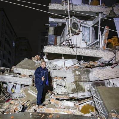 Henkilö seisoo romahtaneen rakennuksen raunioissa.