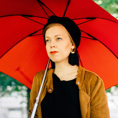 Viitasen Piia -yhtyeen laulaja-lauluntekijä Piia Viitanen lähikuvassa punaisen sateenvarjonalla.