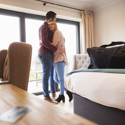 Man och kvinna står i hotellrum och kramas