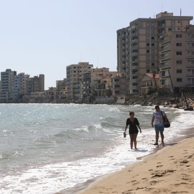 Folk som promenerar längs med en övergiven strand i Cypern. 