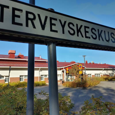 Polvijärven terveyskeskuksen piha syyskuisena päivänä. Etualalla kyltti.