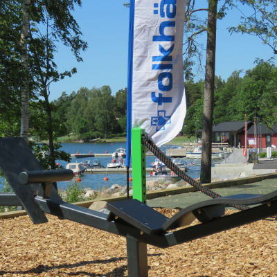 Ett gymredskap ute på ett utegym. En båthamn och hav i bakgrunden.