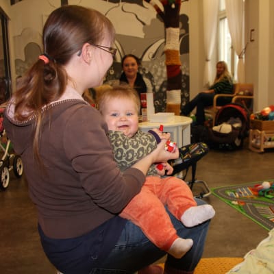 Vauva istuu äidin sylissä.