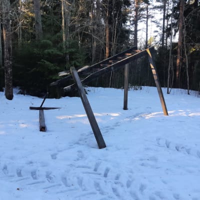 Skadat träningsredskap av trä med traktorspår bredvid på vintern.