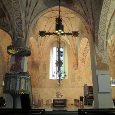 Interiör från Sankt Lars kyrka i Lojo. I förgrunden ses Jesus på korset, i bakgrunden skymtar altaret.