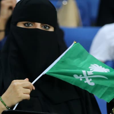 En saudisk kvinna med Saudiarabiens flagga i handen.