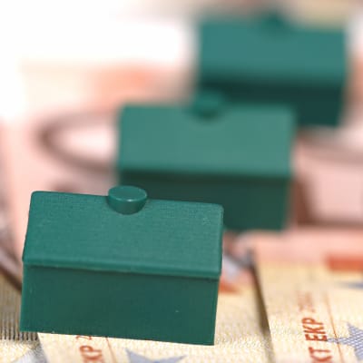 Tre gröna Monopolhus i rad på eurosedlar.