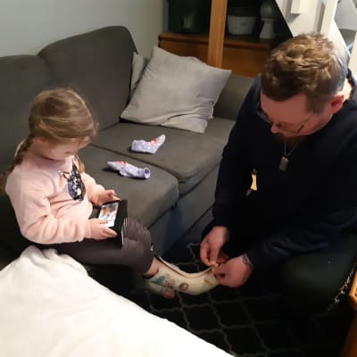 Pappa Jonny Kivelä sätter en specialsko på dottern Lee Kiveläs fot.