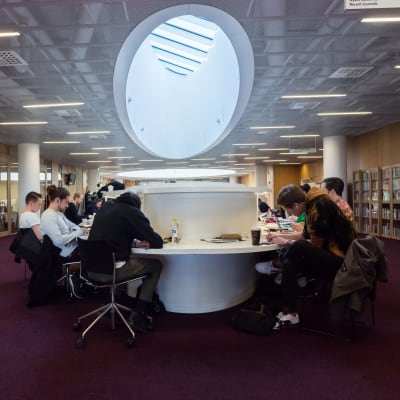 Studerande sitter och studerar i Helsingfors universitets huvudbibliotek.