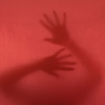 Anonyma händer mot ett rödfärgat fönster.