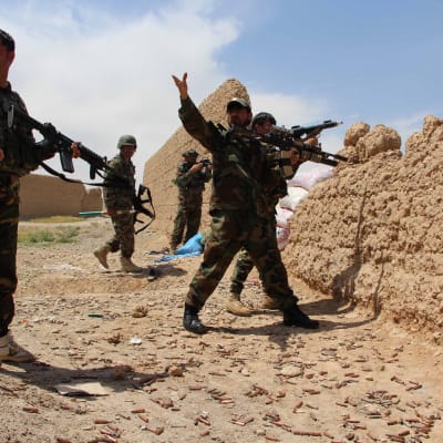 Afghanska soldater säker skydd bakom en mur under strider mot taliban-gerillan i Helmand-provinsen.