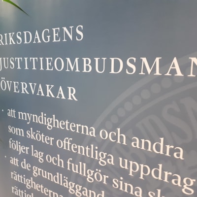 En skylt i riksdagen med texten Riksdagens justitieombudsman övervakar, och exempel på något område 