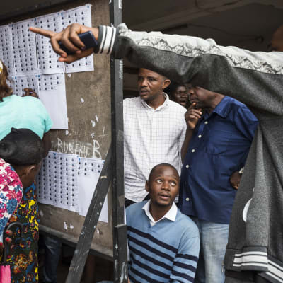 Väljare letar efter sina namn på valrullor i en vallokal i huvudstaden Kinshasa