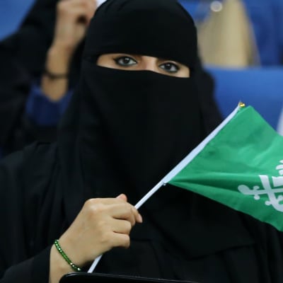 En saudisk kvinna med Saudiarabiens flagga i handen.