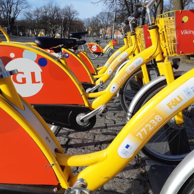 en lång rad gula cyklar i samma cykelställ på ett stentorg i Åbo