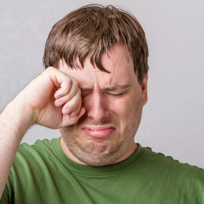 En man torkar tårar med handen från sina ögon.