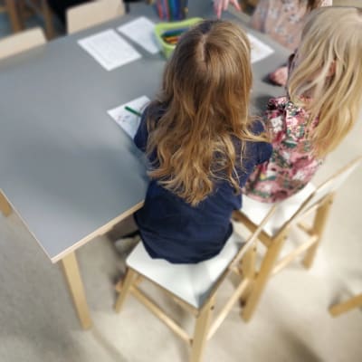 Kuvassa on kaksi päiväkoti-ikäistä tyttöä. 