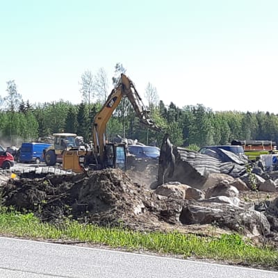 En grävmaskinist lyfter mattor som används vid sprängning på Ingåport.
