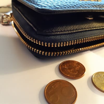 En blå plånbok med några utfällda mynt på ett bord