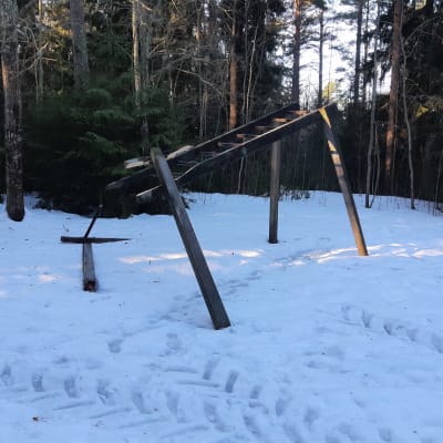 Skadat träningsredskap av trä med traktorspår bredvid på vintern.