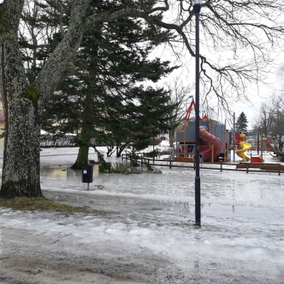 En lekpark för barn på vintern då marken är täckt av is och vatten.