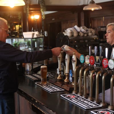 Asiakas maksaa luottokortilla oluen lontoolaisessa pubissa. 