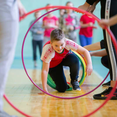 En pojke tar sig igenom en hinderbana av hula hula-ringar på en skolgymnastiklektion.