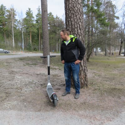 En man står och tittar på en elsparkcykel, Fredrik Bäcklund.