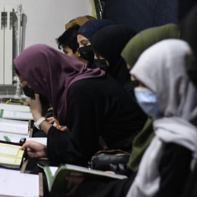 Joukko huiveihin kietoutuneita tyttöjä opiskelee Koraania luokkahuoneessa.