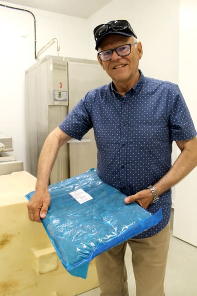 Man i blå skjorta står med ett paket i händerna.
