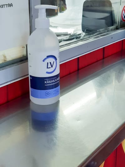 Flaska med handsprit står på disken av rostfritt stål i en grillkiosk.
