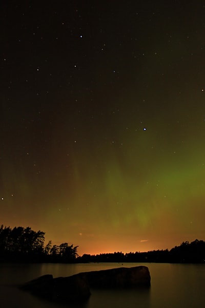 Stjärnhimlen färgas orange och delvis grön av norrsken i Borgå den 25 september 2023.