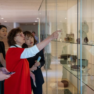 Karin Widnäs visar upp konstverk i ett vitrinskåp i sitt museum Kwum.