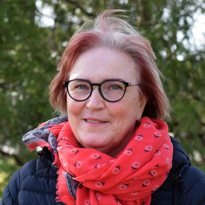 Kvinna står framför träd. 